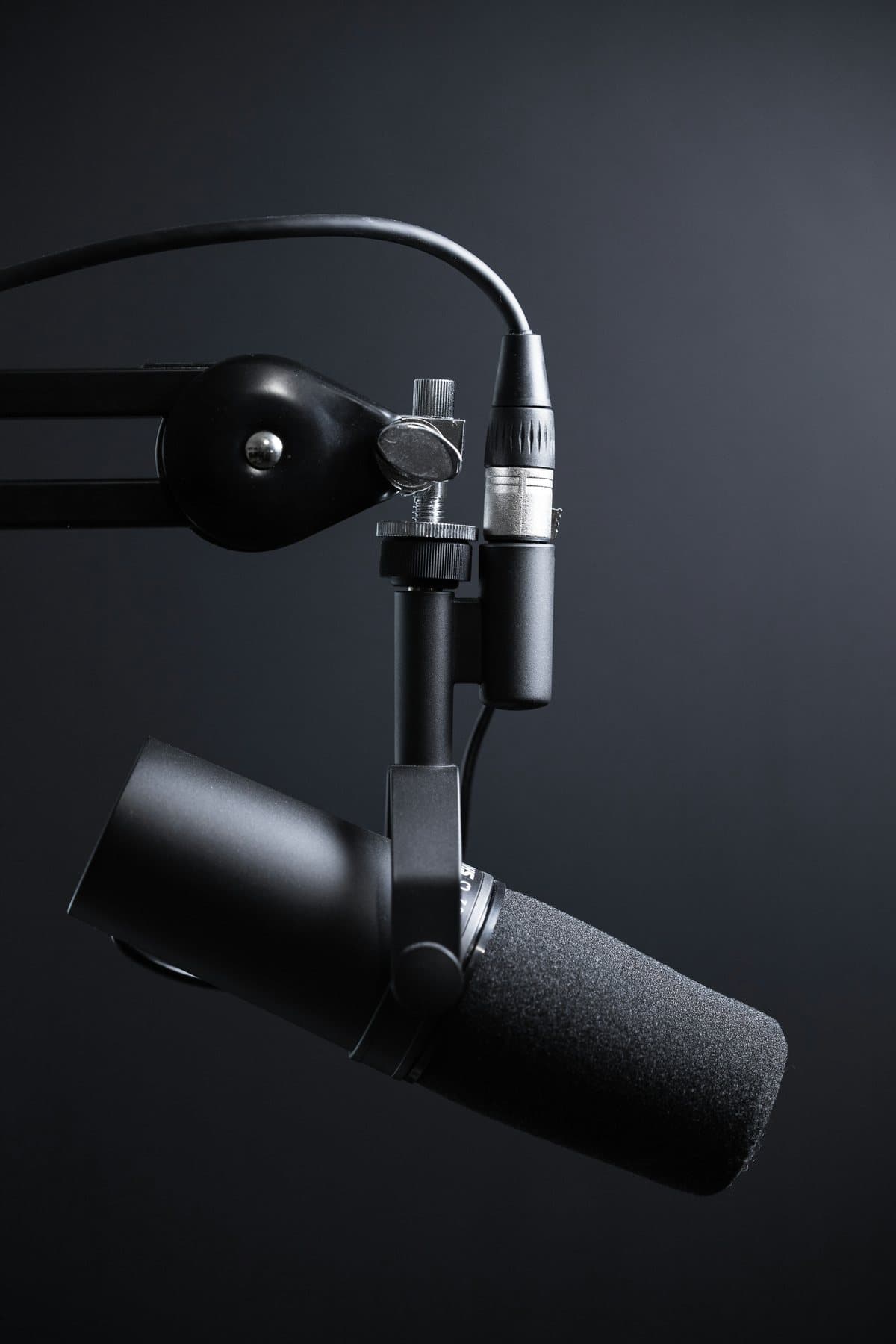 Shure broadcast microphone on a boom arm against a dark background