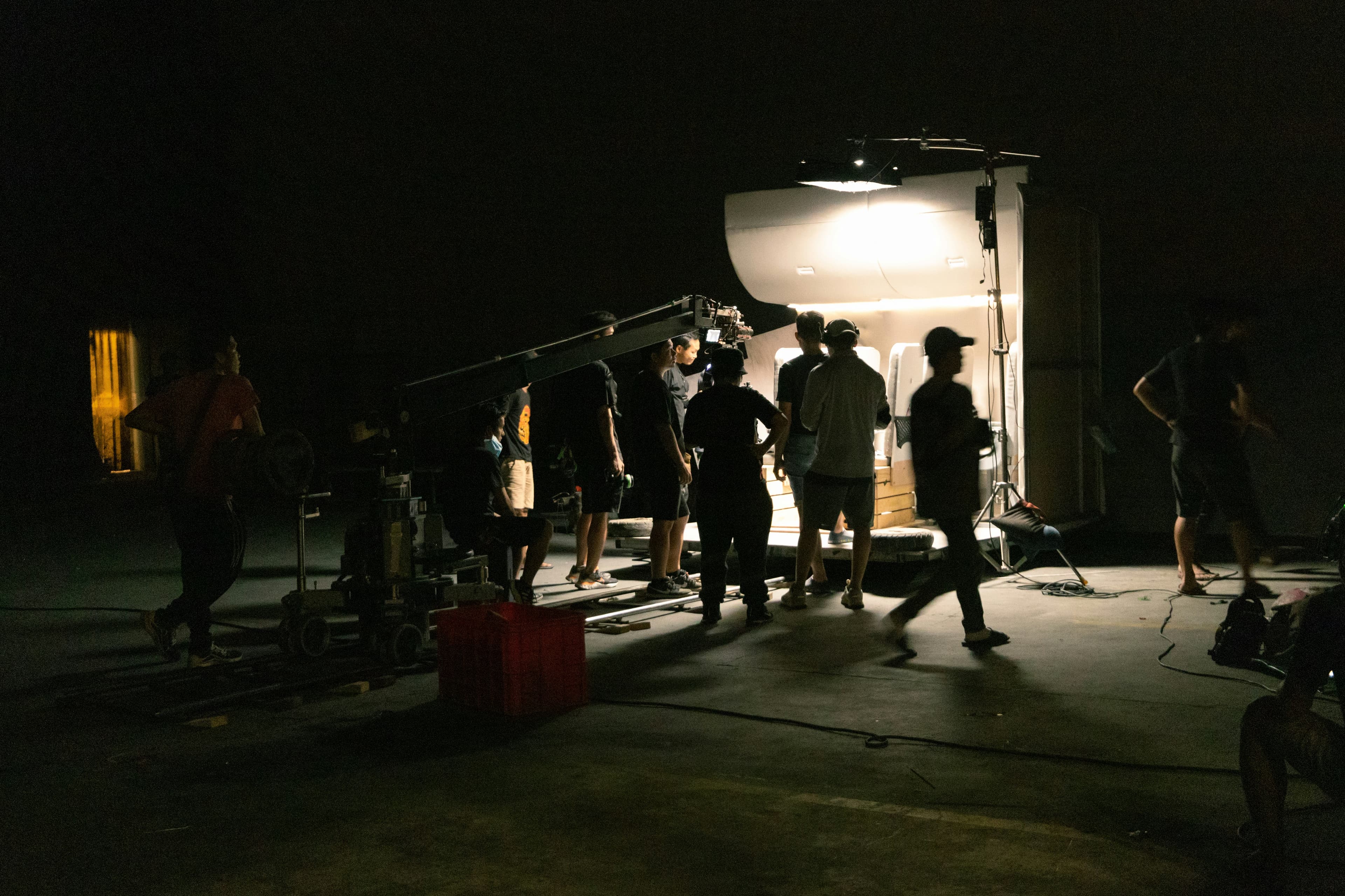 Film crew gathered around a camera in a dark set
