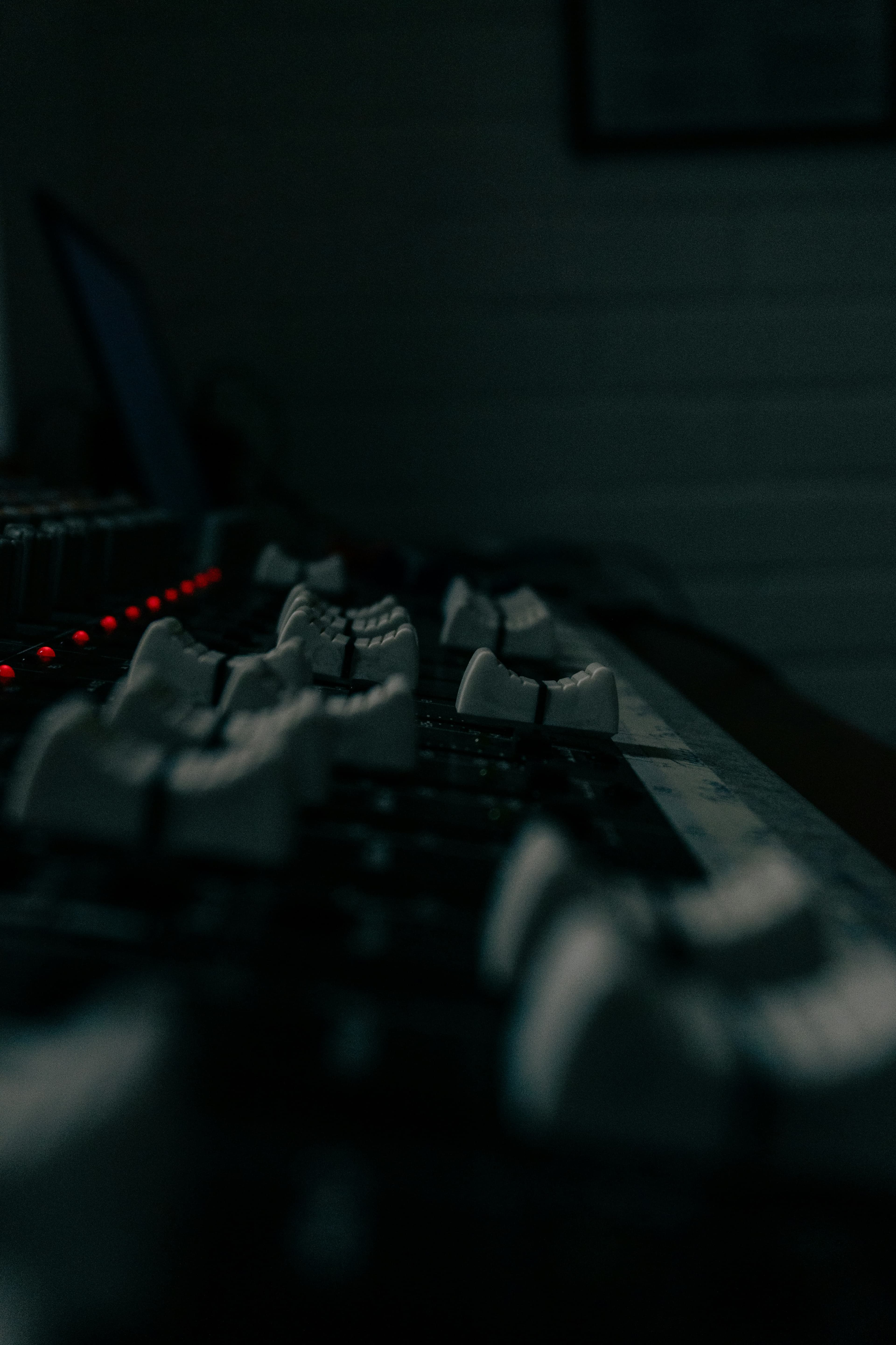 Mixing console faders glowing red in a dark control room