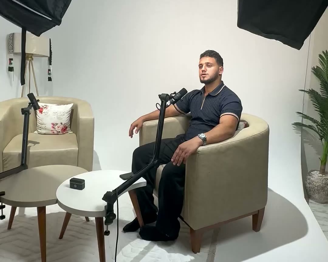 A guest seated in the Tunisia Studios set as the camera glides past lights and microphones